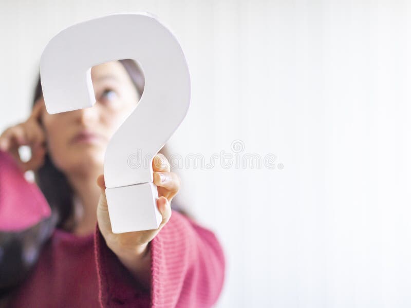 Question mark sign hold by a caucasian young woman with red sweater and thinking or confusion expression. Communication, decision or respond concept. Copy space. Question mark sign hold by a caucasian young woman with red sweater and thinking or confusion expression. Communication, decision or respond concept. Copy space