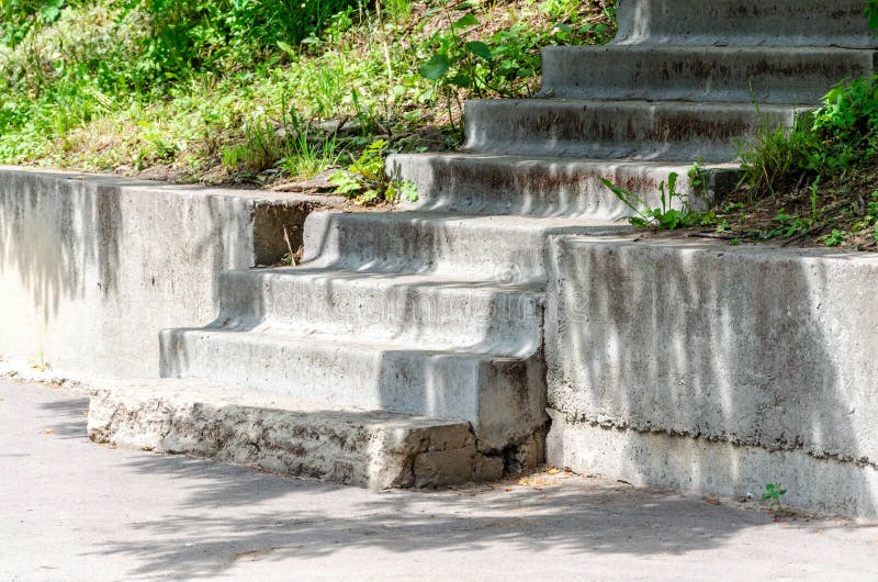 Zniszczeni starzy betonowi schodki w parku, betonowe p?yty, curbstone, zielona trawa, drzewa zdjęcie stock Zniszczeni starzy betonowi schodki w parku, betonowe p?yty, curbstone, zielona trawa, drzewa zdjęcie stock