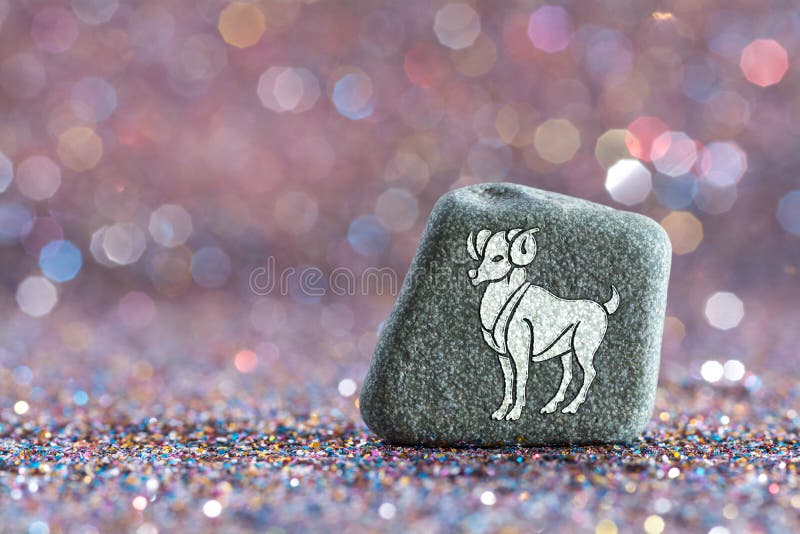 a green stone with Aries zodiac sign on glitter boke light background. a green stone with Aries zodiac sign on glitter boke light background