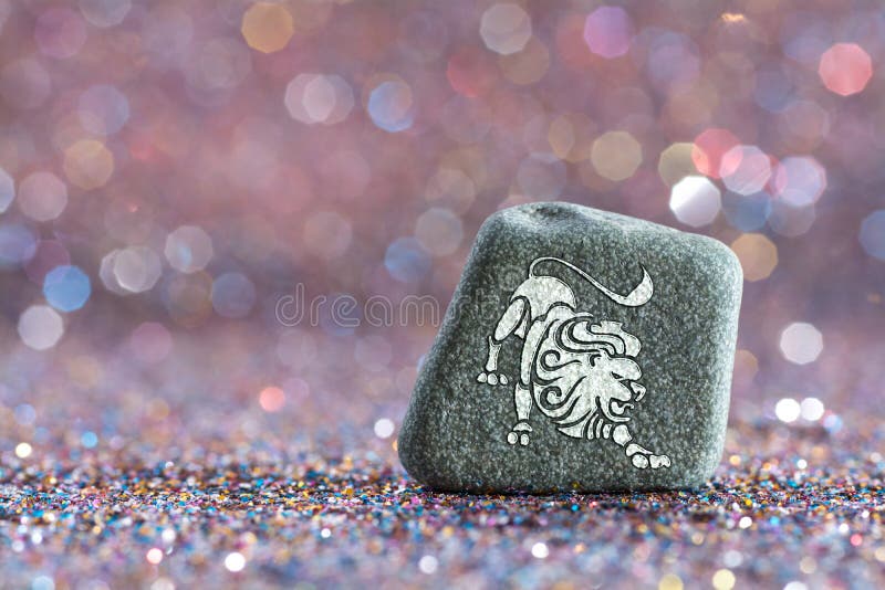 A green stone with Leo zodiac sign on glitter boke light background. A green stone with Leo zodiac sign on glitter boke light background