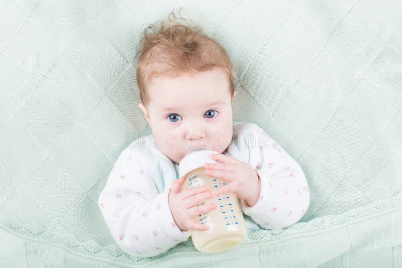Zoete baby met grote blauwe ogenconsumptiemelk stock fotografie Zoete baby met grote blauwe ogenconsumptiemelk stock fotografie