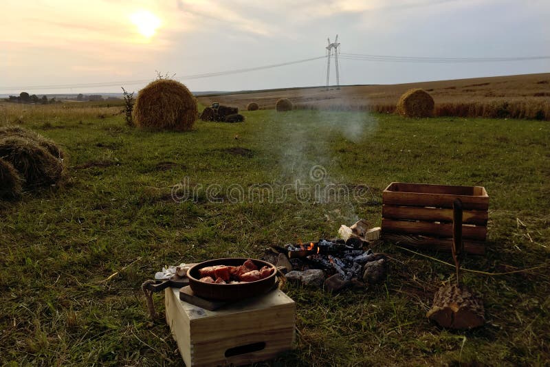 Zomer picknick in de avond in het veld, rietstapels en geoogste tarwe Vlees is in brand gestoken, het vuur brandt neer royalty-vrije stock afbeelding Zomer picknick in de avond in het veld, rietstapels en geoogste tarwe Vlees is in brand gestoken, het vuur brandt neer royalty-vrije stock afbeelding