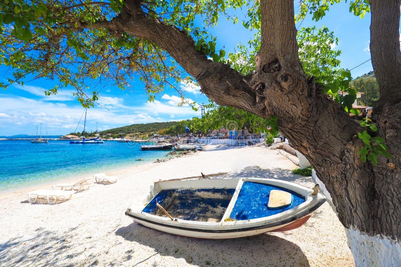 Zonnig de zomerstrand in Griekenland met zonbedden en kleine boot royalty-vrije stock afbeeldingen Zonnig de zomerstrand in Griekenland met zonbedden en kleine boot royalty-vrije stock afbeeldingen
