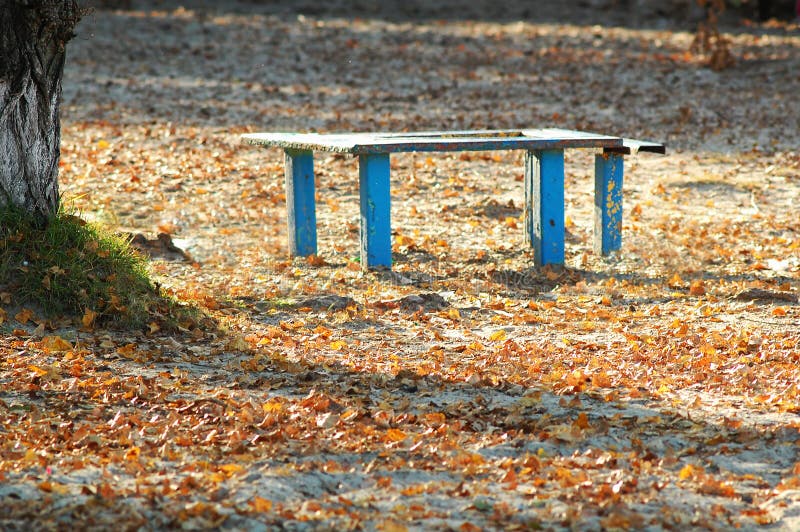 Zonovergoten oude blauwe houten bank en lijst bij een park van het de herfststrand Zonnige dag royalty-vrije stock foto Zonovergoten oude blauwe houten bank en lijst bij een park van het de herfststrand Zonnige dag royalty-vrije stock foto