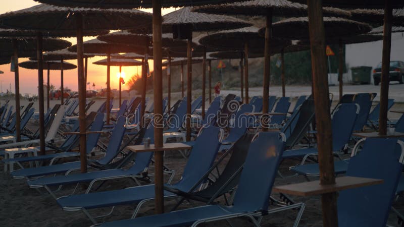 Zonsondergangscène van strand met stroparaplu's en lege chaise-longues