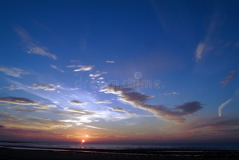 Sunrise near alnmouth, northumberland, England,showing sun's disc, dramatic multi-coloured sky and clouds, and calm sea. Sunrise near alnmouth, northumberland, England,showing sun's disc, dramatic multi-coloured sky and clouds, and calm sea