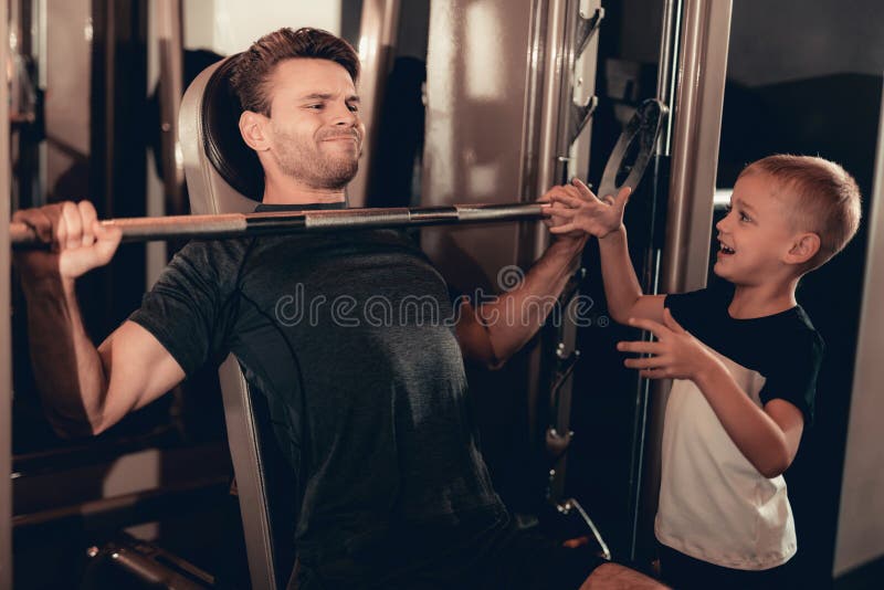 Zoonssteun aan Vader While Lifting The Barbell stock afbeelding Zoonssteun aan Vader While Lifting The Barbell stock afbeelding