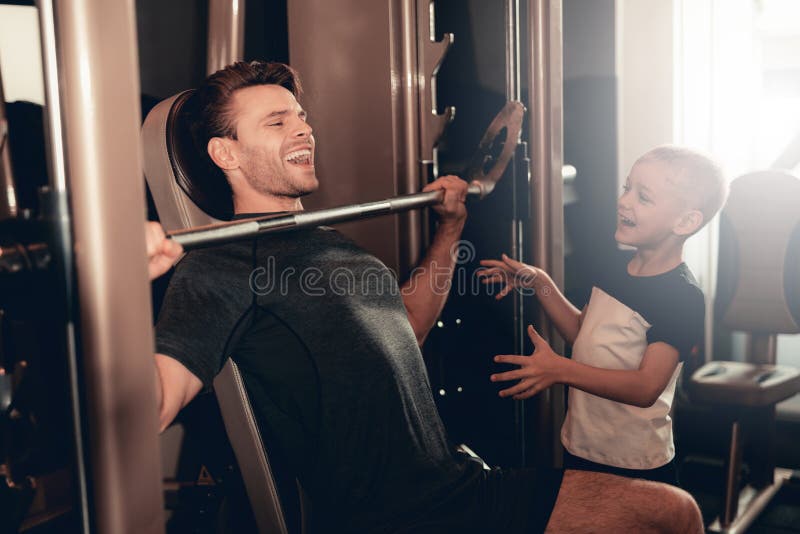 Zoonssteun aan Vader While Lifting The Barbell stock fotografie Zoonssteun aan Vader While Lifting The Barbell stock fotografie
