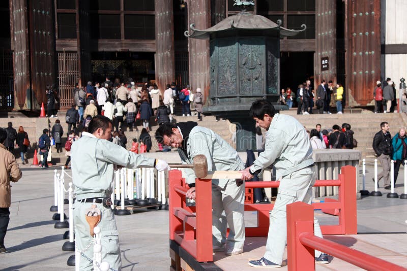Three Japanese carpenter are construction the stage, Using a wooden hammer strike to the components of the stage. royalty free stock photo