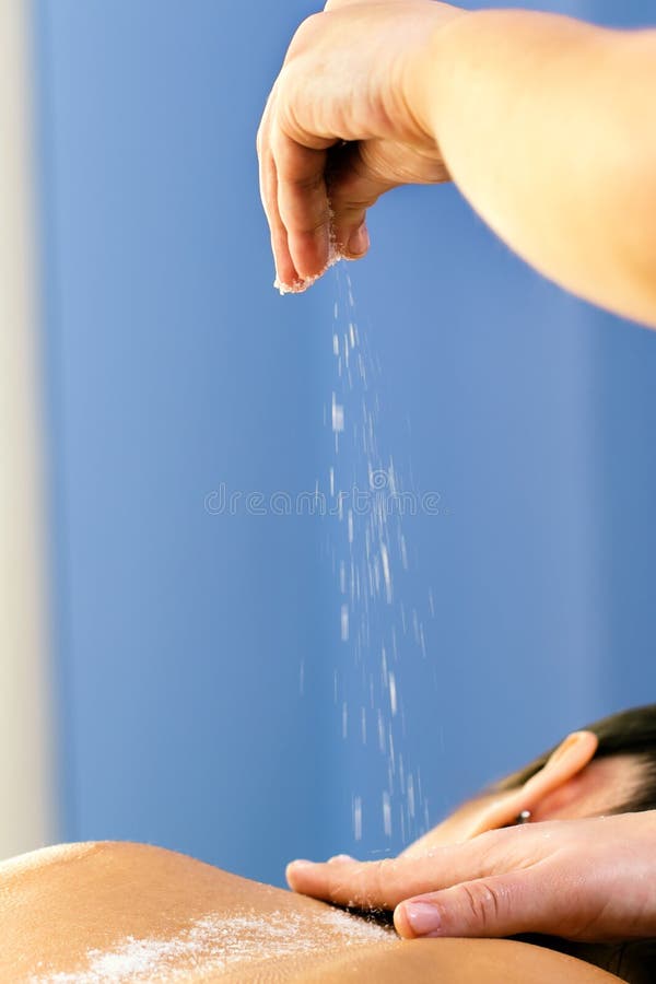 Zout van de therapeut het gietende afschilfering op vrouwelijke rug stock fotografie Zout van de therapeut het gietende afschilfering op vrouwelijke rug stock fotografie