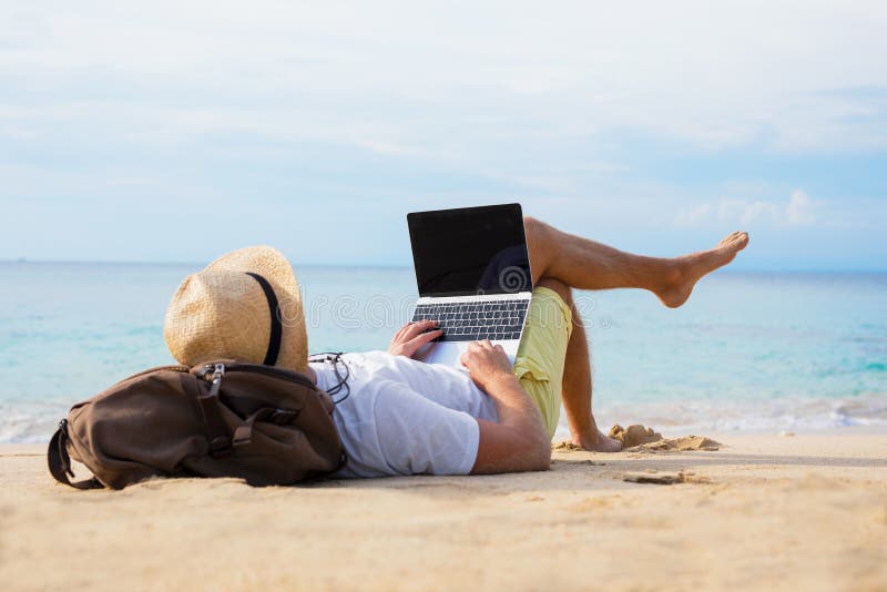 Zrelaksowany mężczyzna z laptopem na plaży fotografia stock Zrelaksowany mężczyzna z laptopem na plaży fotografia stock