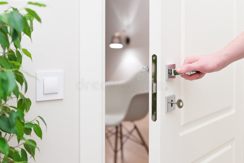 Zu die Tür öffnen Moderne weiße Tür mit Chrommetallgriff und ein Mann ` s bewaffnen lizenzfreie stockfotografie