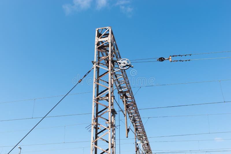 Zug- oder EisenbahnStromleitung Unterstützung Bahnstromleitungen mit Hochspannungsstrom auf Metallpfosten gegen blauen Himmel stockbild Zug- oder EisenbahnStromleitung Unterstützung Bahnstromleitungen mit Hochspannungsstrom auf Metallpfosten gegen blauen Himmel stockbild