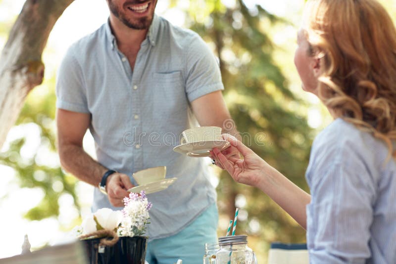 Zugeschnittenes Bild von bärtigen Ehemann geben eine Tasse Kaffee zu seiner Frau mit Lächeln