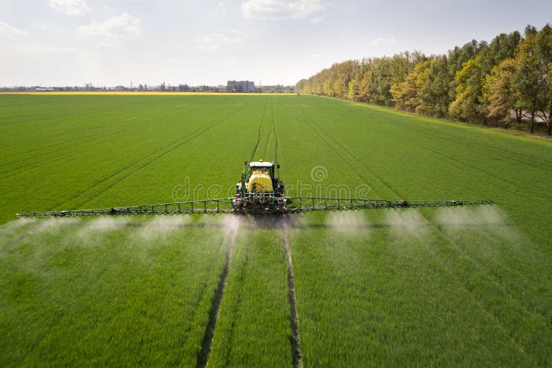 Tractor spraying chemical pesticides with sprayer on the large green agricultural field at spring. Tractor spraying chemical pesticides with sprayer on the large green agricultural field at spring.