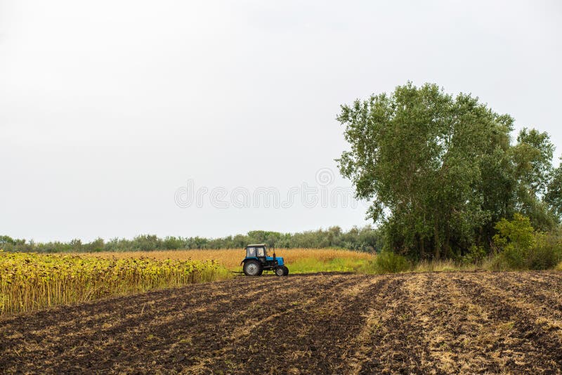 A tractor plows a field with a plow. Rural landscape of an agricultural country. Sow season. A tractor plows a field with a plow. Rural landscape of an agricultural country. Sow season.