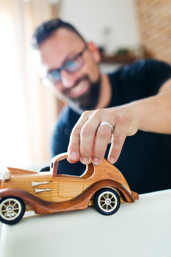 Zurück in der Kindheit, Mann, der mit hölzernem Spielzeugauto spielt lizenzfreies stockfoto Zurück in der Kindheit, Mann, der mit hölzernem Spielzeugauto spielt lizenzfreies stockfoto