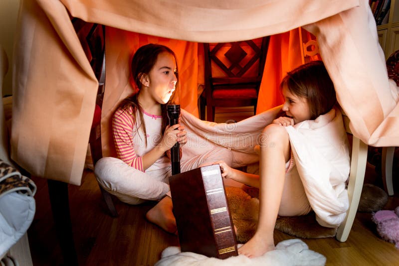 Two sisters telling scary stories under blanket at night. Two sisters telling scary stories under blanket at night