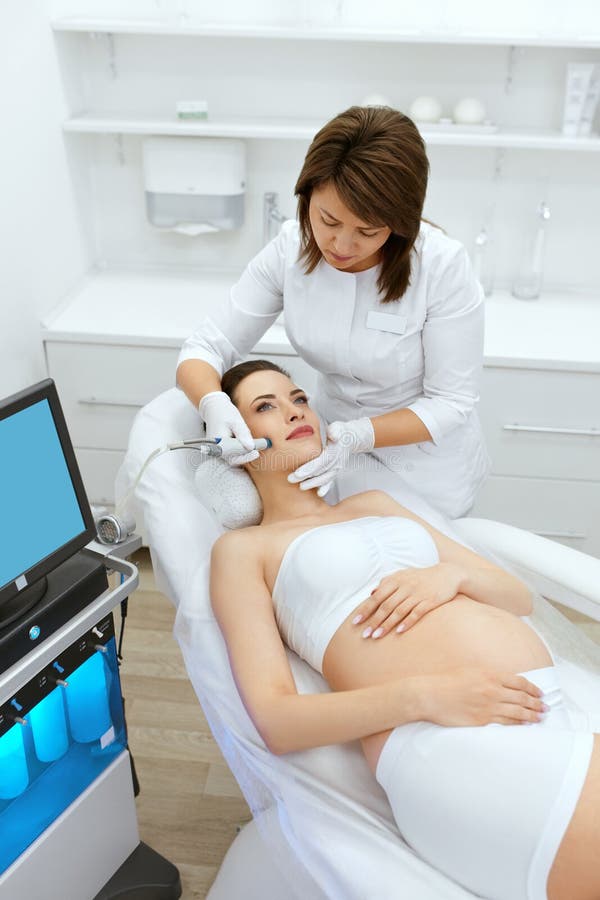 Zutreffen des transparenten Lacks Schwangere Frau auf Gesicht reinigend an der Schönheits-Klinik