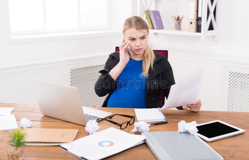 Zwangere bedrijfsdame bij de documenten van de het werklezing stock afbeelding Zwangere bedrijfsdame bij de documenten van de het werklezing stock afbeelding
