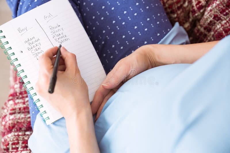 Pregnant woman listing baby names at home in the living room. Pregnant woman listing baby names at home in the living room