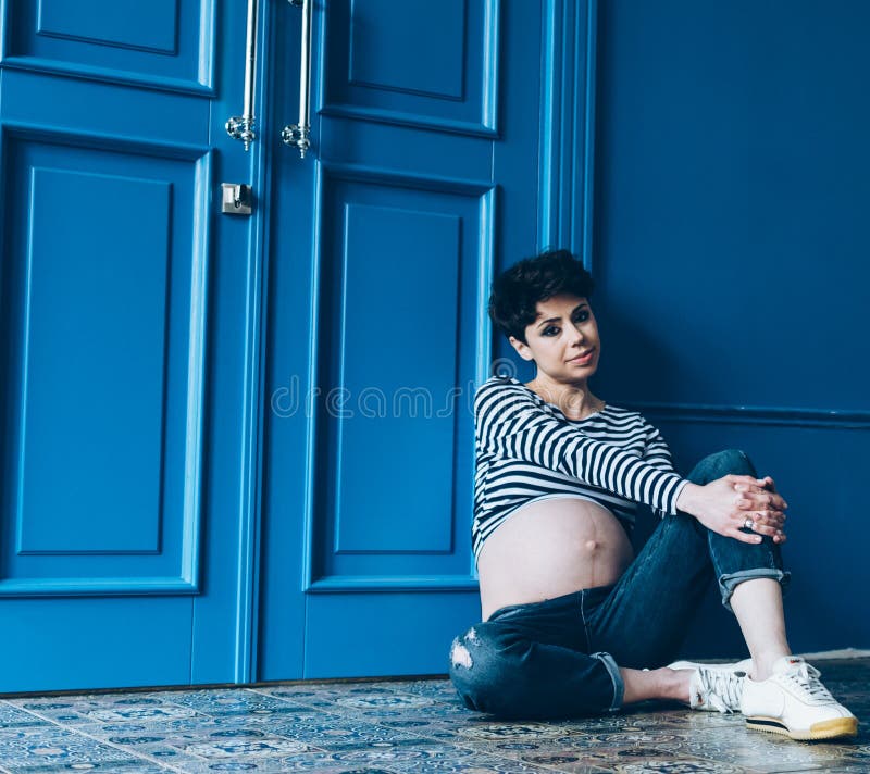 Zwangere het glimlachen vrouwenzitting op houten vloer in ruimte moederschap motherhood stock fotografie Zwangere het glimlachen vrouwenzitting op houten vloer in ruimte moederschap motherhood stock fotografie