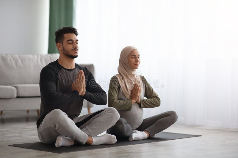 Zwangere moslimvrouw in hijab die samen met haar man thuis mediteert