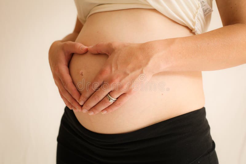 8 month pregnant woman forming a heart on her belly with her hands. 8 month pregnant woman forming a heart on her belly with her hands.