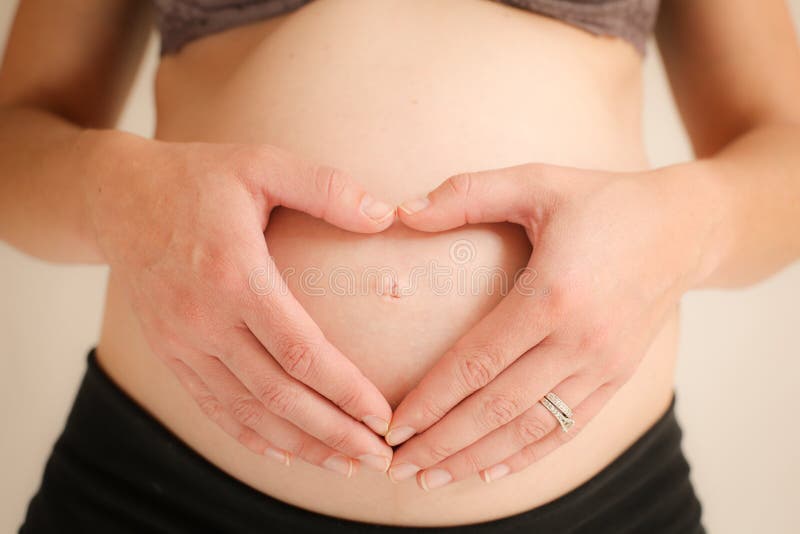 8 month pregnant woman forming heart with hands on her tummy. 8 month pregnant woman forming heart with hands on her tummy.