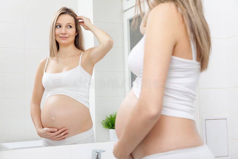 Zwangere vrouw in badkamersspiegel stock afbeelding Zwangere vrouw in badkamersspiegel stock afbeelding