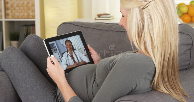 Zwangere vrouw die aan arts op tablet spreken stock afbeeldingen Zwangere vrouw die aan arts op tablet spreken stock afbeeldingen