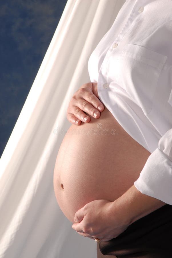 A pregnant woman's belly with her hands on it. A pregnant woman's belly with her hands on it.