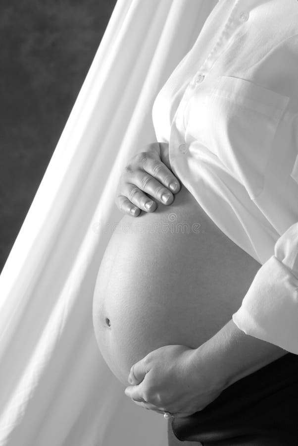 A pregnant woman's belly with her hands on it. A pregnant woman's belly with her hands on it.