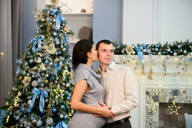 Zwangerschap, de wintervakantie en mensenconcept - gelukkige zwangere vrouw met echtgenoot thuis bij Kerstmis royalty-vrije stock foto's Zwangerschap, de wintervakantie en mensenconcept - gelukkige zwangere vrouw met echtgenoot thuis bij Kerstmis royalty-vrije stock foto's