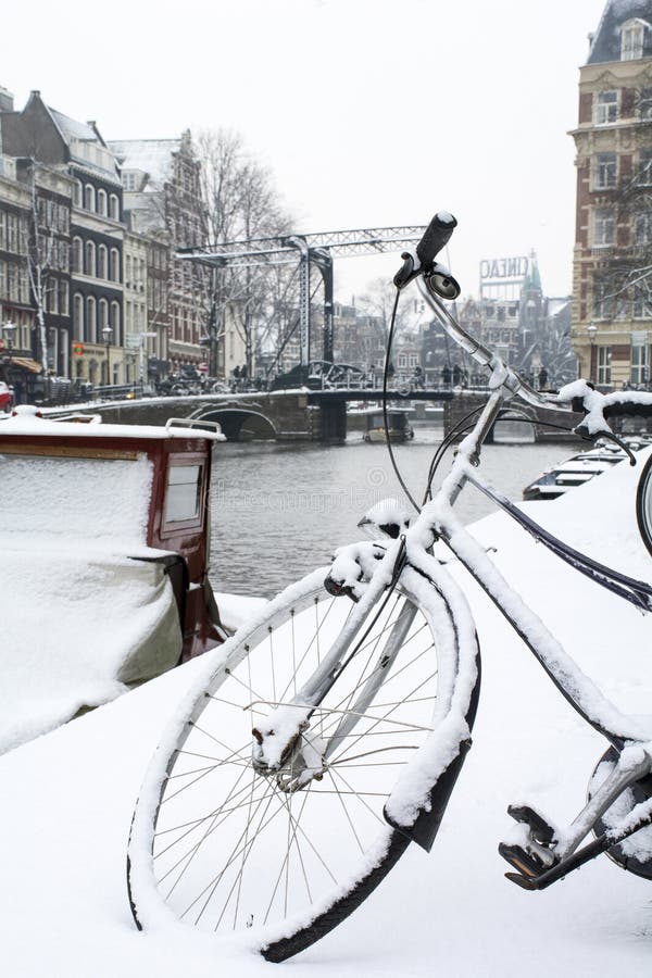 Zwart fietswiel in sneeuw in Amsterdam met kanaal en brug stock foto's Zwart fietswiel in sneeuw in Amsterdam met kanaal en brug stock foto's