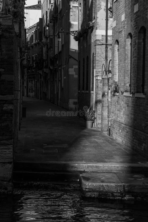 High Contrast Lighting Photo of a charming Narrow Street and Canal in Venice, Italy. High Contrast Lighting Photo of a charming Narrow Street and Canal in Venice, Italy