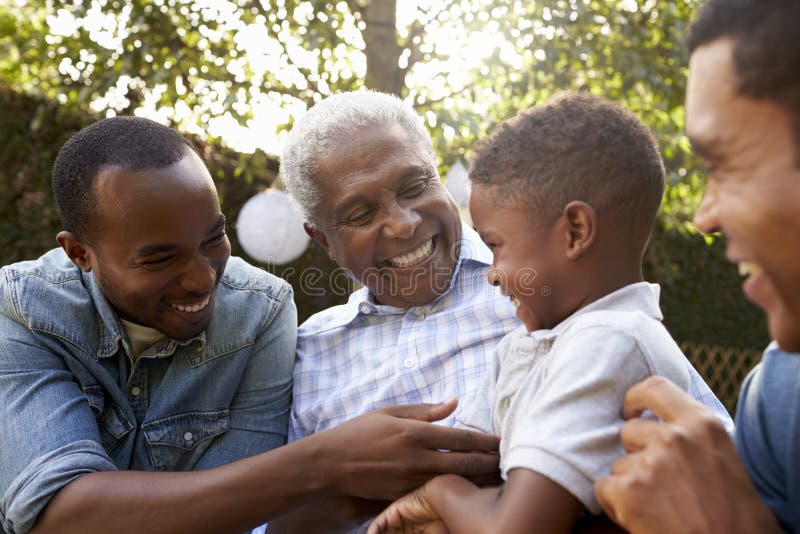 Zwarte grootvader, zonen en kleinzoon die in een tuin spreken