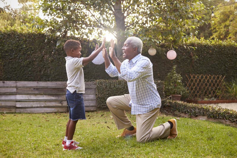 Zwarte grootvaderspelen met kleinzoon in tuin, volledige lengte