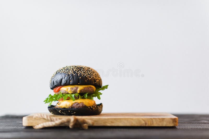 Zwarte Hamburger op houten Hakbord, grijze achtergrond royalty-vrije stock afbeelding Zwarte Hamburger op houten Hakbord, grijze achtergrond royalty-vrije stock afbeelding