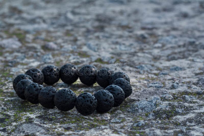 Zwarte lava armband op een steenparapet