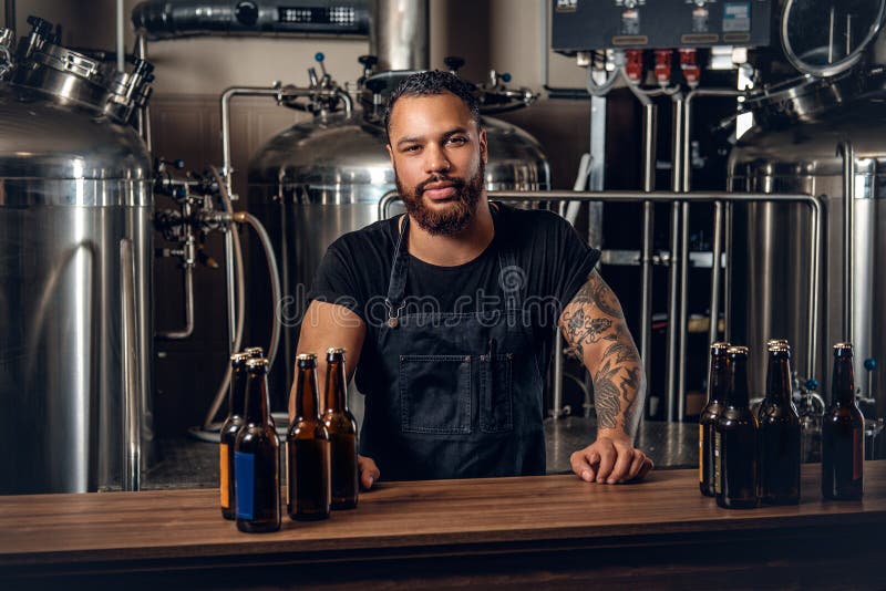 Zwarte mensenfabrikant die ambachtbier in microbrewery voorstellen stock afbeeldingen Zwarte mensenfabrikant die ambachtbier in microbrewery voorstellen stock afbeeldingen