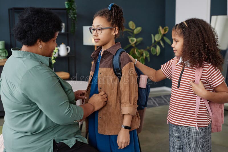 Side view portrait of Black senior women helping girl with backpack getting ready for school. Side view portrait of Black senior women helping girl with backpack getting ready for school