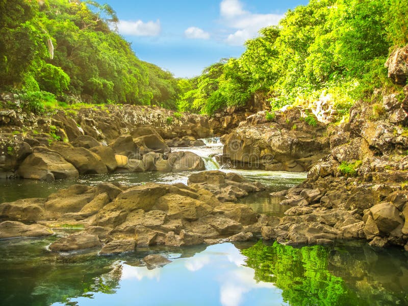 Beautiful sky reflected in the calm waters of Black River Gorges National Park, the largest protected forest of Mauritius, Indian Ocean, Africa. Scenic landscape of popular travel destination. Beautiful sky reflected in the calm waters of Black River Gorges National Park, the largest protected forest of Mauritius, Indian Ocean, Africa. Scenic landscape of popular travel destination.