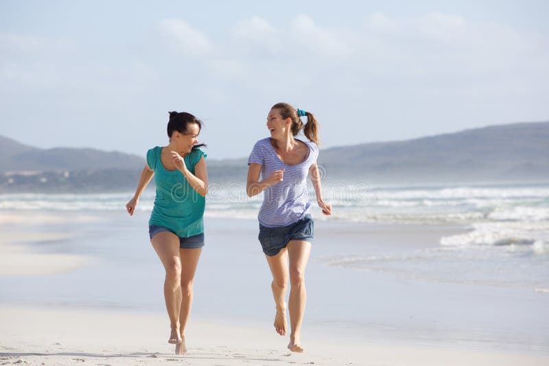 Zwei aktive Frauen, die das Leben am Strand laufen lassen und genießen stockfotografie Zwei aktive Frauen, die das Leben am Strand laufen lassen und genießen stockfotografie