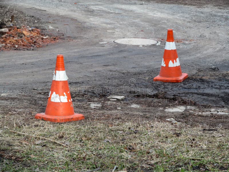 Zwei alte schäbige Baukegel sind auf einem Schotterweg Orange Verkehrskegel mit schäbigen weißen Streifen vor dem hintergrund lizenzfreies stockbild Zwei alte schäbige Baukegel sind auf einem Schotterweg Orange Verkehrskegel mit schäbigen weißen Streifen vor dem hintergrund lizenzfreies stockbild