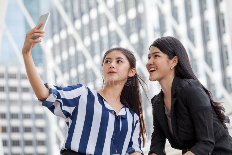 Zwei asiatische Freundinnen, die selfie Foto mit Smartphone in städtischem machen stockbild Zwei asiatische Freundinnen, die selfie Foto mit Smartphone in städtischem machen stockbild
