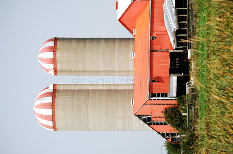 Two farm silos and an orange barn. Two farm silos and an orange barn