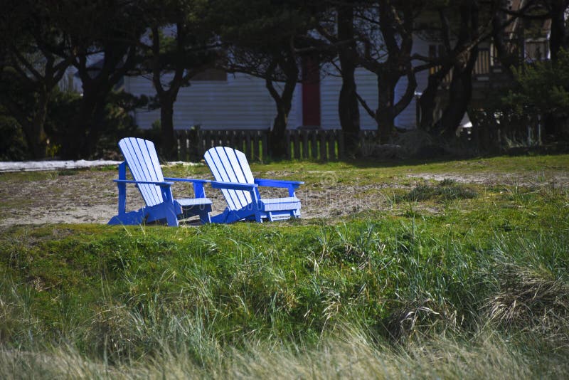 Zwei blaue Adirondack-Stühle auf einem Strand stockbild Zwei blaue Adirondack-Stühle auf einem Strand stockbild