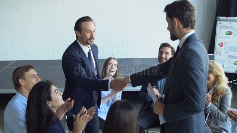 Zwei der Geschäftsmann-Händedruck während der Sitzung tut sich Vereinbarungs-Konzept, Chef With Team Of Businesspeople Working To