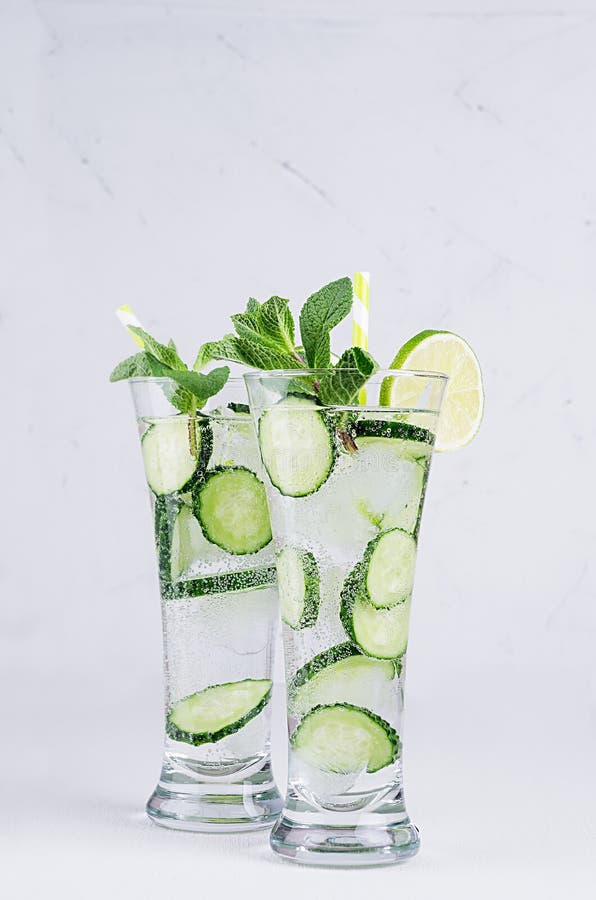 Zwei Eleganzgläser mit kaltem Detox wässern mit Scheiben Gurke, Kalk, Minze, Eis, Stroh auf weißer hölzerner Planke, Nahaufnahme stockbilder Zwei Eleganzgläser mit kaltem Detox wässern mit Scheiben Gurke, Kalk, Minze, Eis, Stroh auf weißer hölzerner Planke, Nahaufnahme stockbilder